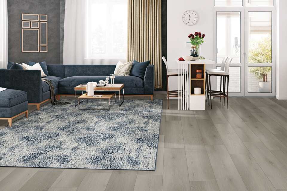 blue animal print area rug in living room with gray walls, blue couch and gray luxury vinyl plank